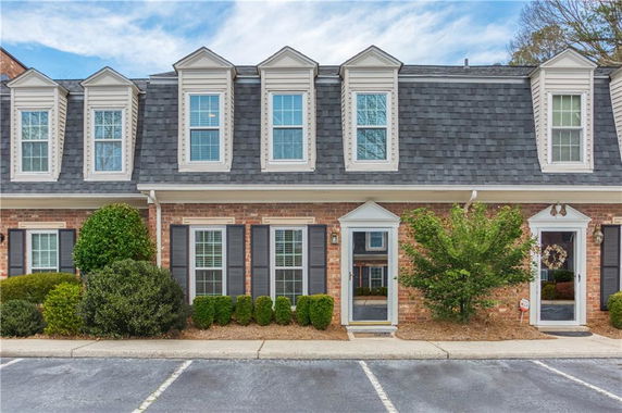 Front view of a two-story townhouse with dormer windows and a brick exterior.