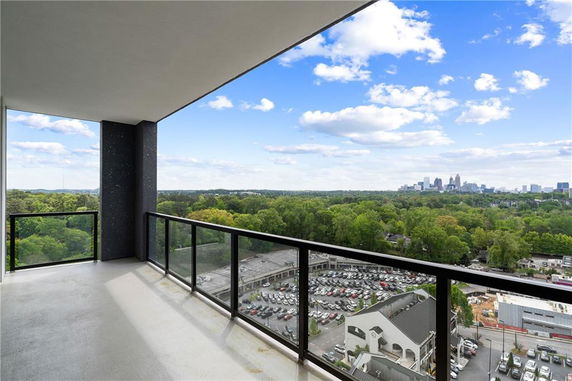 Balcony view overlooking lush greenery and distant city skyline.