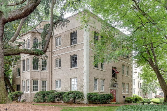 Front view of a multi-story brick building with multiple windows and an arched entrance.