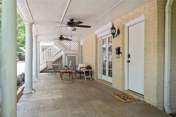 Covered patio area with ceiling fans and seating in front of a building entrance.