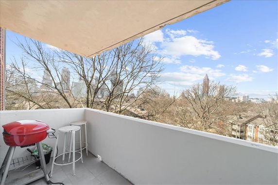 Balcony view overlooking city skyline and trees.