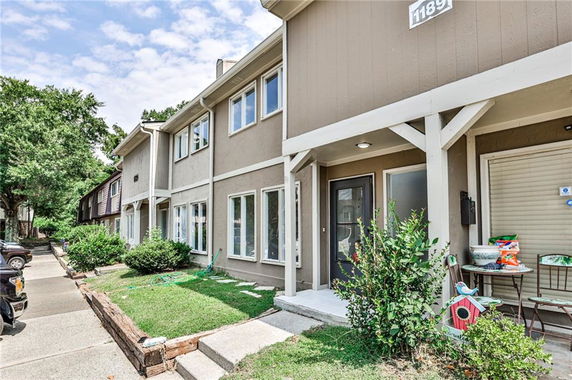 Front view of a two-story townhouse with a small garden and porch.