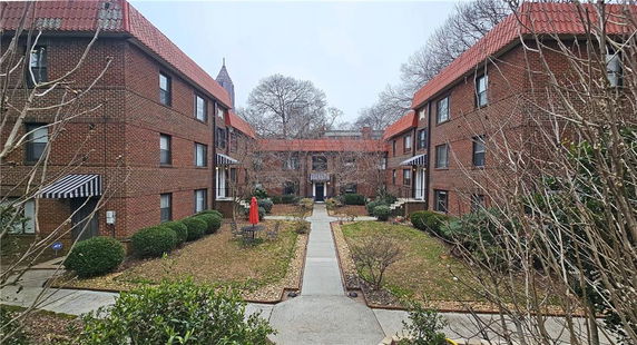 View of a three-story brick apartment building with red tiled roofs.