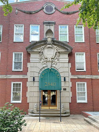 Front view of a brick building with white trim and an entrance with a green awning labeled Crestwood 2840.