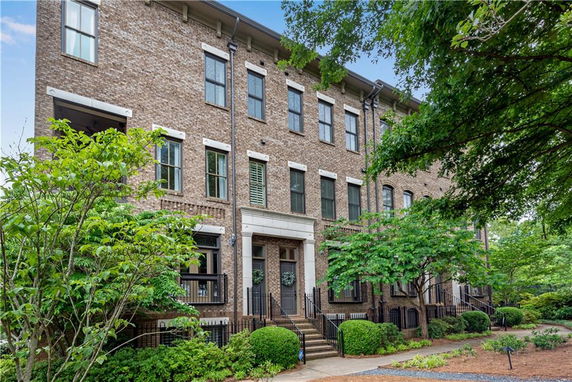 Front view of a three-story brick townhouse with multiple windows and entry steps.