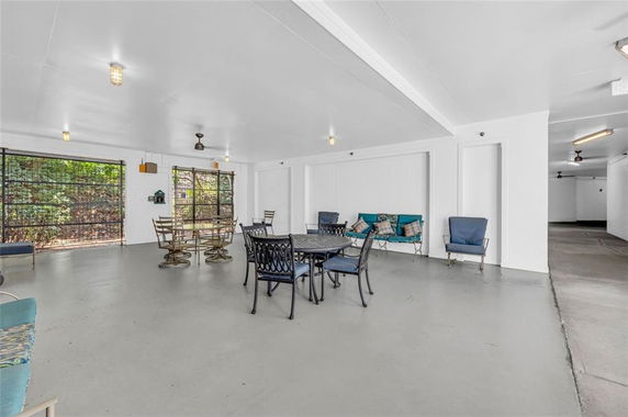Indoor recreation area with tables, chairs, and seating against white walls.