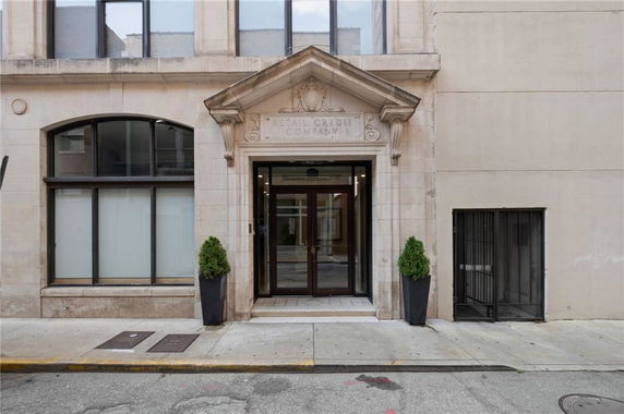 Front view of a building entrance with large windows and decorative stonework.