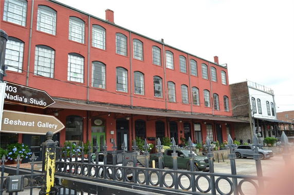 Front view of a red brick multi-story building with large windows and a flat roof.