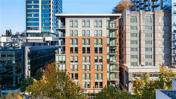 Front view of a multistory residential building with a brick exterior and large windows.