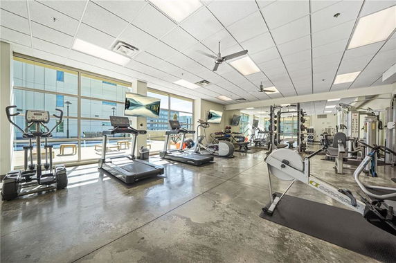 Interior of a gym with various exercise equipment and large windows.
