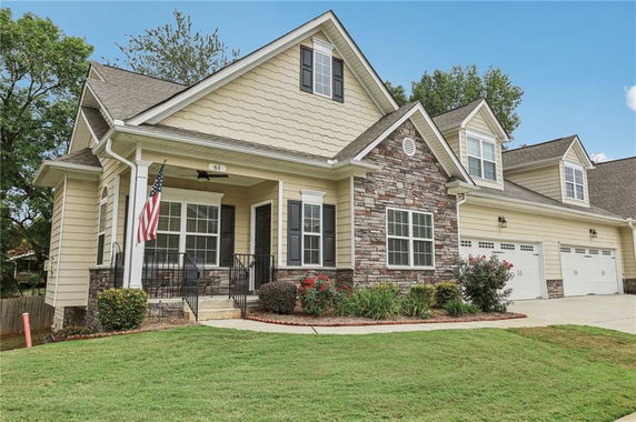 Front view of a two-story house with stone and siding exterior and a three-car garage.