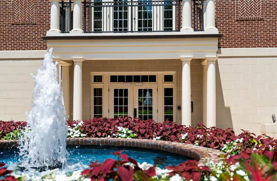 Front view of a building with a decorative entrance featuring columns and a water fountain.