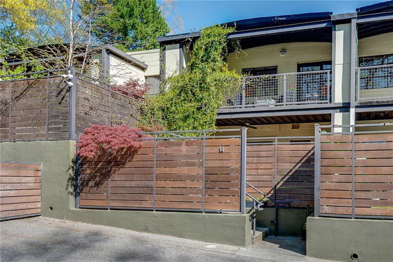 Front view of a house with a balcony, surrounded by a wooden fence.