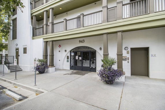 Front view of a multi-story building with balconies and an arched entrance.
