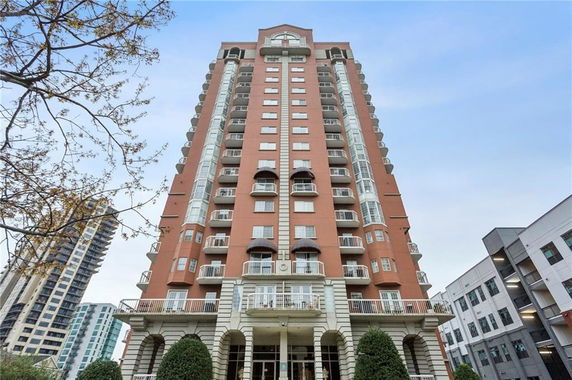 Front view of a multi-story residential building with balconies and arched entrances.