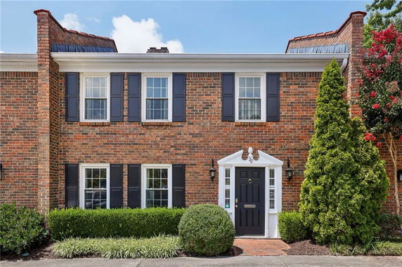 Front view of a two-story brick house with a decorative entrance and black shutters.