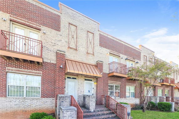 Front view of a multi-story townhouse with brick facade and metal balconies.