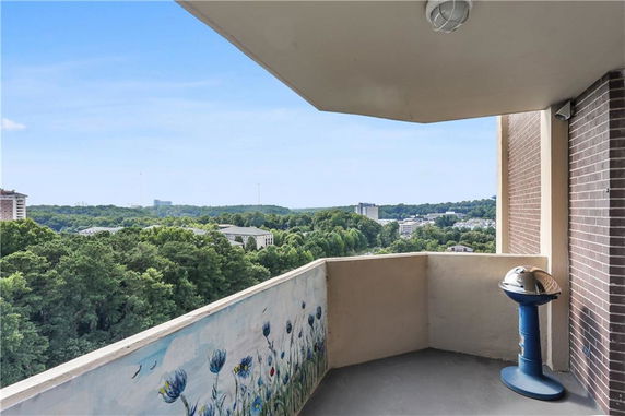 Balcony view of surrounding greenery and distant buildings.