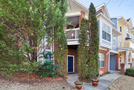 Front view of a townhouse with brick and siding exterior, featuring a small covered balcony.