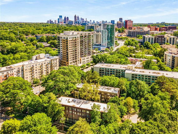 Aerial view of a cityscape with mid-rise and high-rise buildings surrounded by trees and greenery.