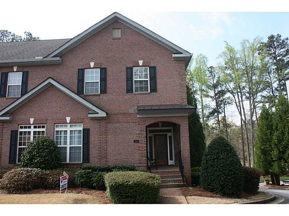 Front view of a two-story brick house with black shutters.