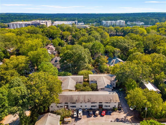 Aerial view of residential buildings surrounded by trees with visible parking and nearby apartment complexes.