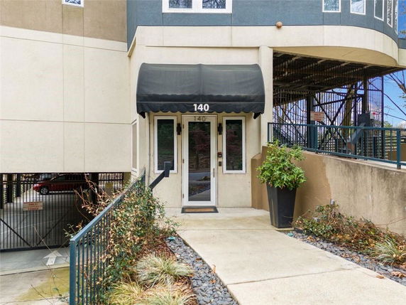 Entrance view of a building with a black awning and a small pathway.