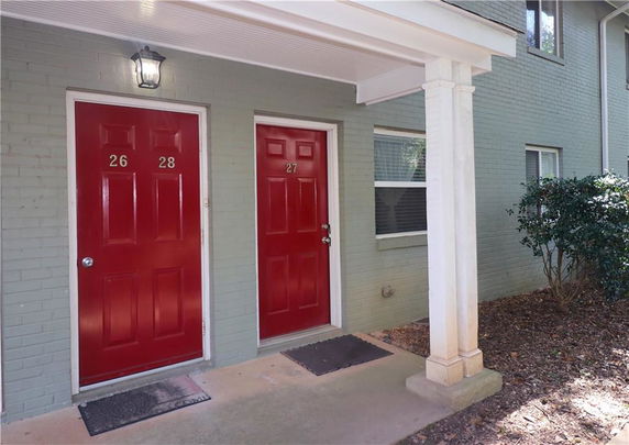 Front view of a building with red doors numbered 26, 27, and 28.