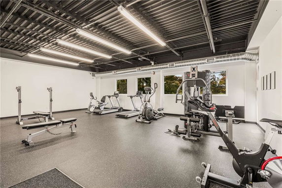 Interior view of a gym with fitness equipment and large windows.