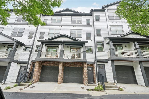 Front view of a multi-story townhouse with garages and balconies.