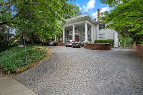 Front view of a large two-story house with multiple columns and a paved driveway.