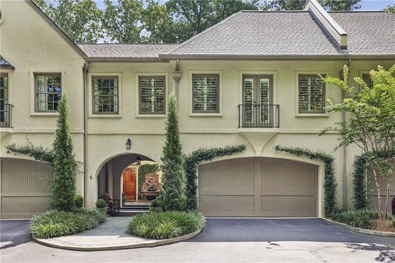 Front view of a two-story house with garage doors and arched entrance.