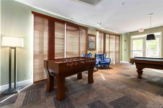 Interior of a room with a foosball table, pool table, and seating area.