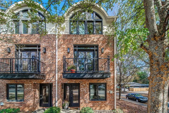 Front view of a multi-story brick townhouse with balconies.