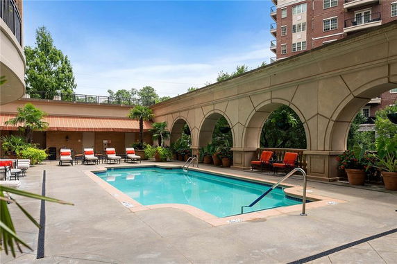 Outdoor swimming pool area with surrounding seating and decorative arches.
