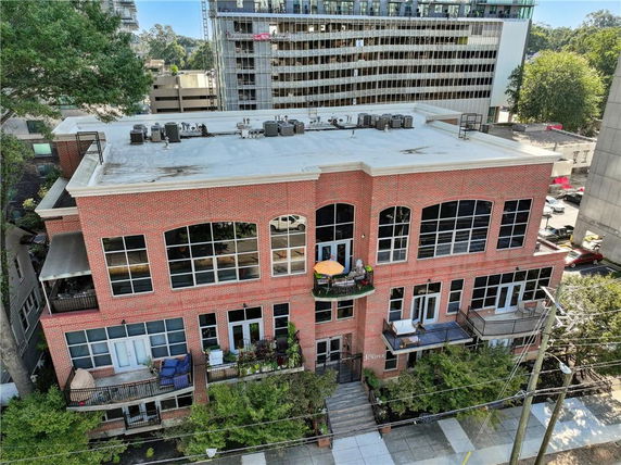 Front view of a three-story brick building with balconies and large windows.