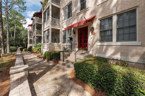 Front view of a multi-story building with balconies and red awnings.