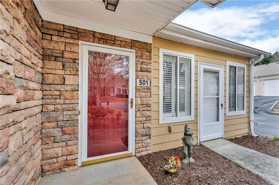 Front view of a house with stone and siding exterior and a glass door entry.