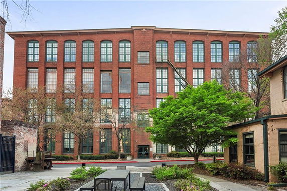 Front view of a multi-story brick building with large windows.