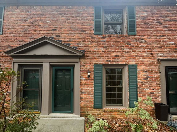 Front view of a two-story brick building with green shutters and two entry doors.