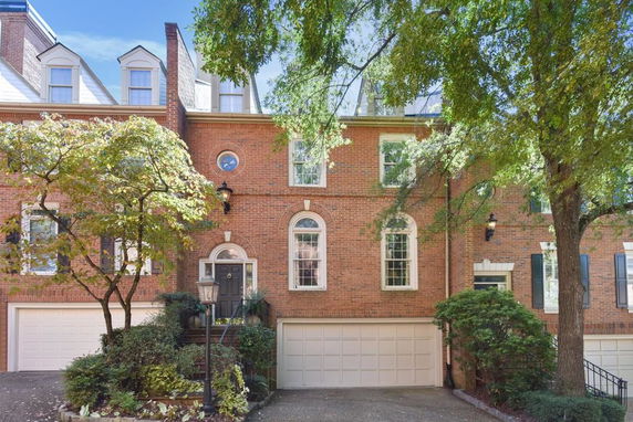 Front view of a multi-story brick townhouse with dormer windows and a double garage.