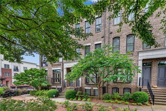Front view of a multi-story brick townhouse with multiple windows and a small front yard.