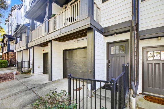 Front view of a multi-story townhome with a balcony and garage.