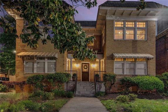 Front view of a two-story brick house with large windows and an awning.