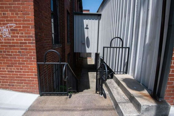 Exterior view of a building with brick and metal siding and an entrance with steps and railings.