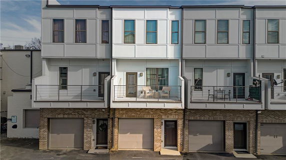 Front view of a multi-story townhouse with balconies and garages.