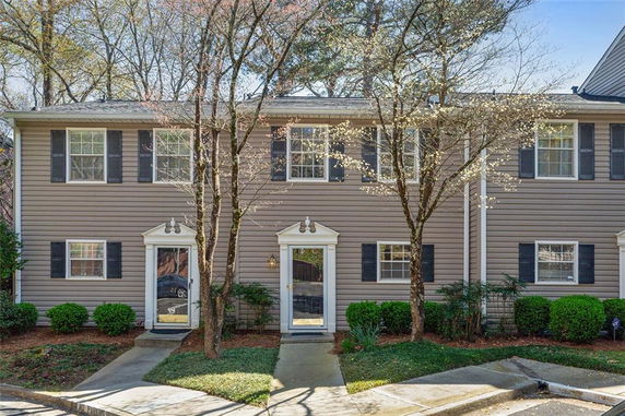 Front view of two-story townhouse with beige siding and black shutters.
