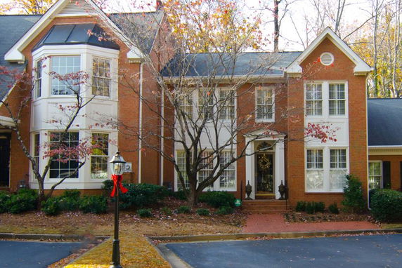 Front view of a two-story brick house with large windows and a central entrance.