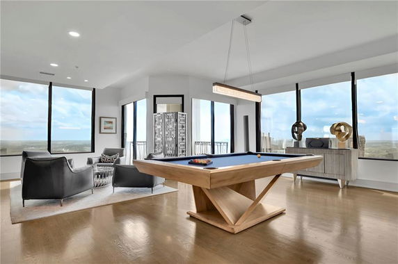 Room featuring a pool table and seating area with large windows.