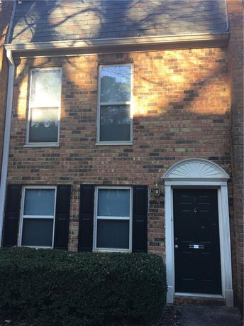 Front view of a brick townhouse with four windows and a black door.